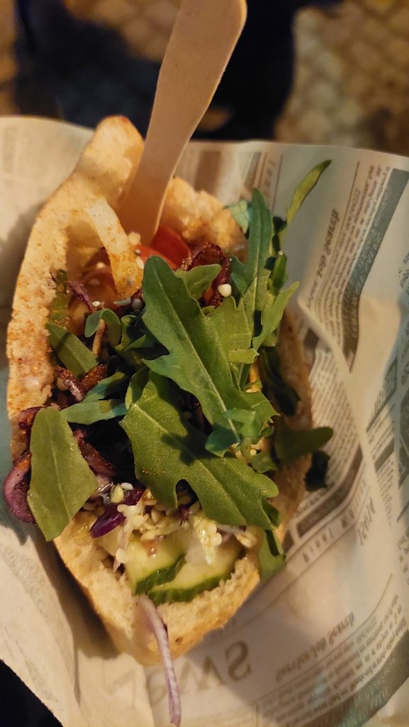 Veganes Pita mit Gurken, Tomaten, Rotkohl, veganen Chunks, Rucola und Hanfsamen.