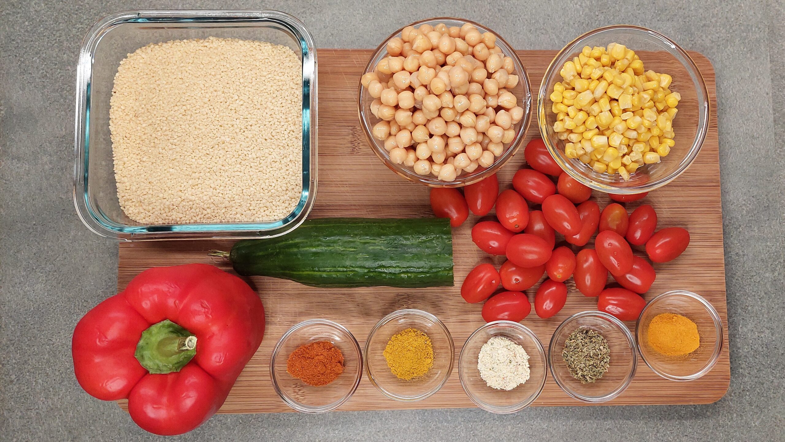 Zutaten für den Couscous-Salat: Couscous, Kirschtomaten, Gurke, Paprika, Kichererbsen, Mais und Gewürze